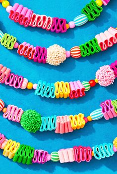 several colorful bracelets are arranged on a blue surface and one is made out of plastic beads