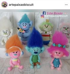 there are many troll dolls on the table together, including one with blue and pink hair