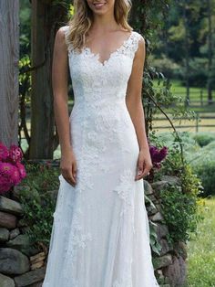 a woman standing in front of a stone wall wearing a wedding dress