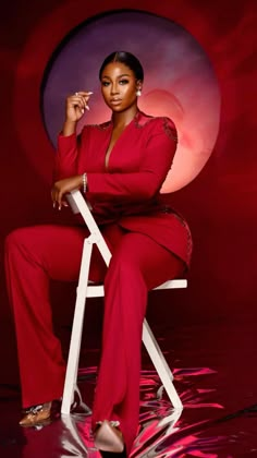 a woman in a red outfit sitting on a chair with her hand on her lip