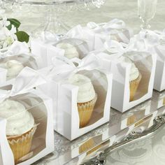 four cupcakes with white frosting in small boxes