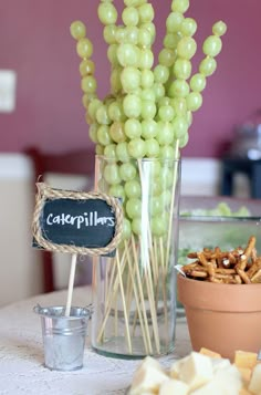 grapes and crackers are sitting on a table next to a glass vase filled with cheese sticks