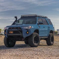 a blue toyota truck parked on top of a gravel field