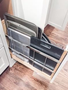 an open dishwasher sitting on top of a wooden floor