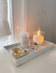 a tray with candles, two gold rings and a candle holder on it that says happy everything