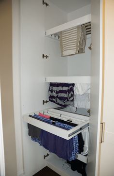 an open closet with clothes hanging on hooks