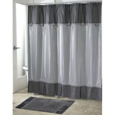 a bathroom with a gray shower curtain and rug on the floor in front of it