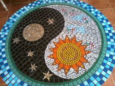 a mosaic table with a sun and moon design on the top, sitting on a tile floor