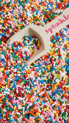 sprinkles are scattered around a wooden spoon with the word sugar on it