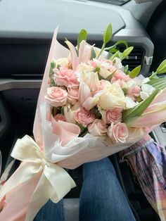 a bouquet of pink and white flowers in someone's lap with the steering wheel behind them