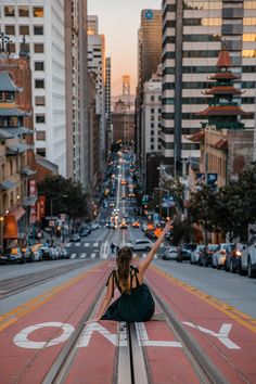 a woman sitting on the side of a road with her arms in the air