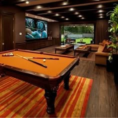 a pool table in the middle of a living room with couches and a flat screen tv