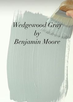 a person holding a paint brush in their hand and the words wedgewod gray by benjamin moore