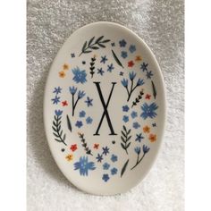 a white plate with blue flowers and the letter x painted on it's side