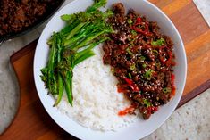 a plate with rice, broccoli and beef on it next to a skillet