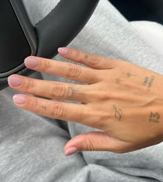 a woman's hand with two small tattoos on her left wrist and right hand