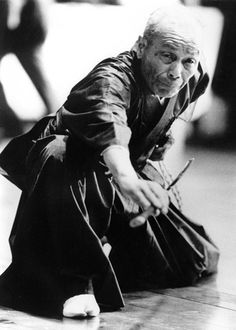 an old man sitting on the ground holding a cane