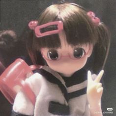 a close up of a doll with big eyes holding a pink object in her hand