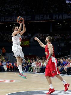 a basketball player jumping up to dunk the ball in front of an audience at a game