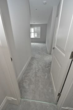 an empty hallway with white walls and carpeted flooring is seen in this image