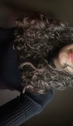 a woman with long curly hair is posing for the camera and has her eyes closed