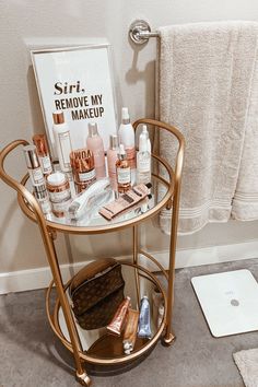 a table with cosmetics and personal care items on it next to a towel rack in a bathroom