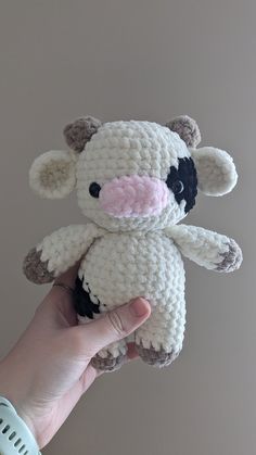 a hand holding a small crocheted cow