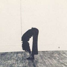 a person standing on one leg in the middle of a room with their head down