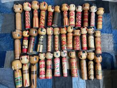 many wooden dolls are lined up on a quilt