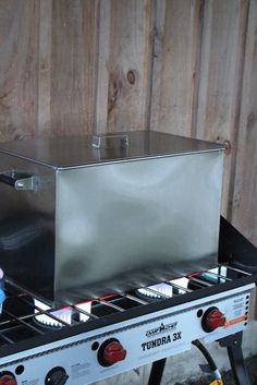 an electric stove sitting on top of a table next to a wooden wall and some wires