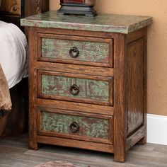 a night stand with two drawers and a lamp on top of it next to a bed