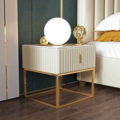 a night stand with a lamp on it next to a bed in a room that has green walls and wood floors