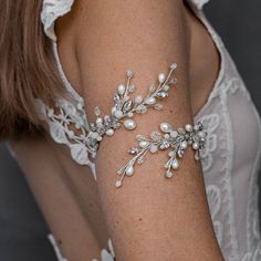 a close up of a woman's arm wearing a bracelet with pearls and leaves