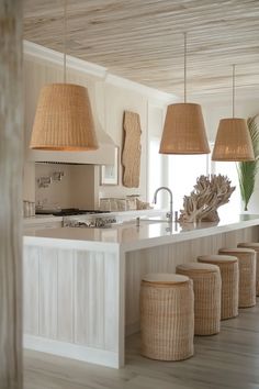 a kitchen with white counter tops and beige lamps hanging from the ceiling over the island