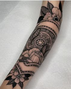 a woman's arm with tattoos on it and flowers in the middle of her arm