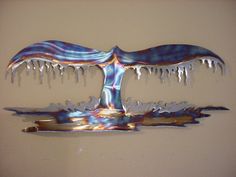 a metal sculpture with icicles hanging from it's sides on a beige wall