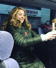 a woman sitting on a bus wearing a green coat