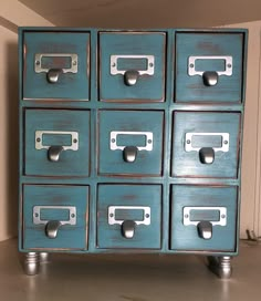 an old blue drawer with metal handles and knobs on the bottom is sitting in front of a white wall