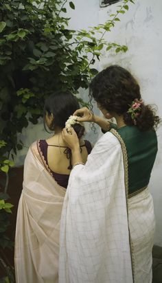 two women standing next to each other with flowers in their hair