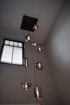 a chandelier with five lights hanging from it's sides in front of a window