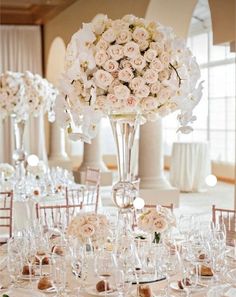 there is a tall vase with white flowers on the table at this wedding reception in an elegant setting