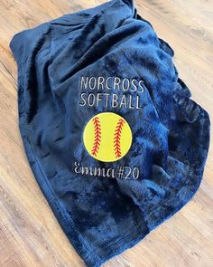 a blue towel with a softball on it sitting on a wooden floor next to a pair of scissors