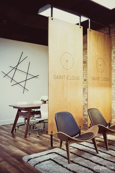 two chairs sitting next to each other on top of a hard wood floor in front of a brick wall