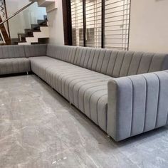 a large gray couch sitting in the middle of a living room next to a stair case