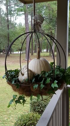 a hanging basket filled with pumpkins and greenery on a porch in the fall