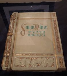 an old book with the words snow white on it sitting in a glass display case