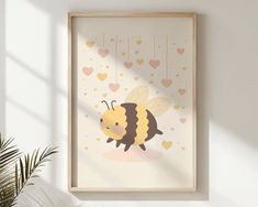 a bee with hearts hanging from it's back on a white wall next to a potted plant