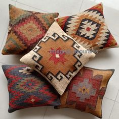 four different colored pillows sitting on top of a white tile floor next to each other