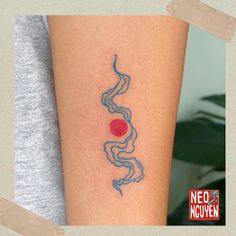 a woman's arm with a tattoo on it that has a red dot in the middle