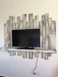 a flat screen tv sitting on top of a wooden shelf next to a white wall